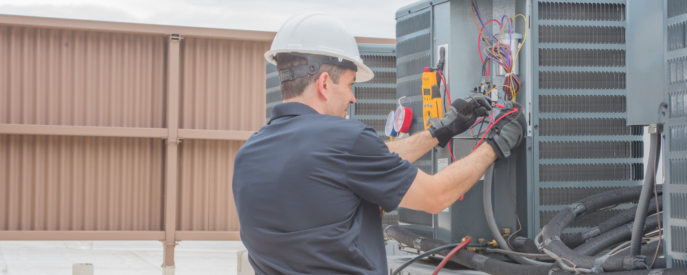 A stock image of a male HVAC technician working on a unit while taking an HVAC training course