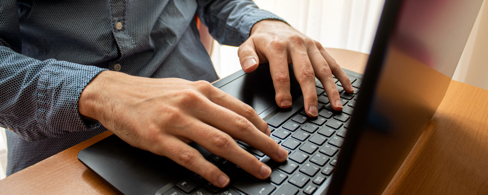 Close-up of hands hovering over the keys of a laptop