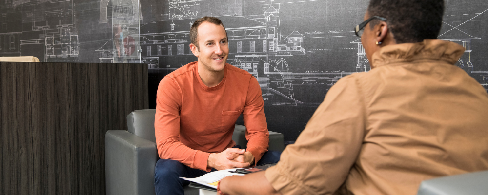 Two people sitting in chairs across from each other, talking and smiling