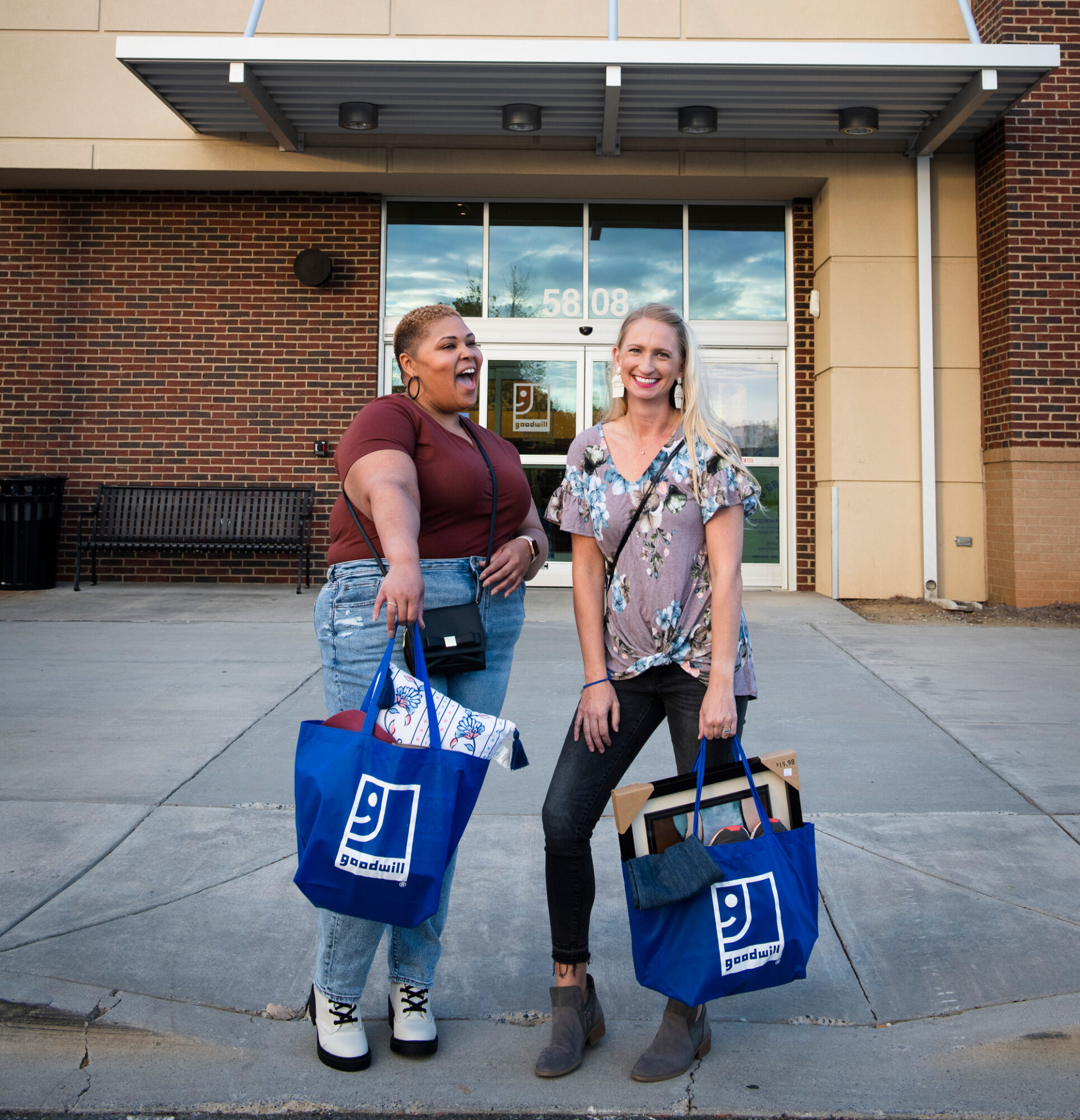 Two friends showing off their haul after shopping at their local Goodwill retail location.